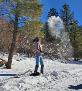 woman marveling at snow thrown in air blue skies