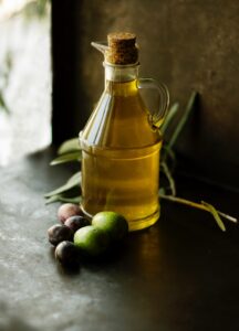 glass flask of olive oil with fresh olives